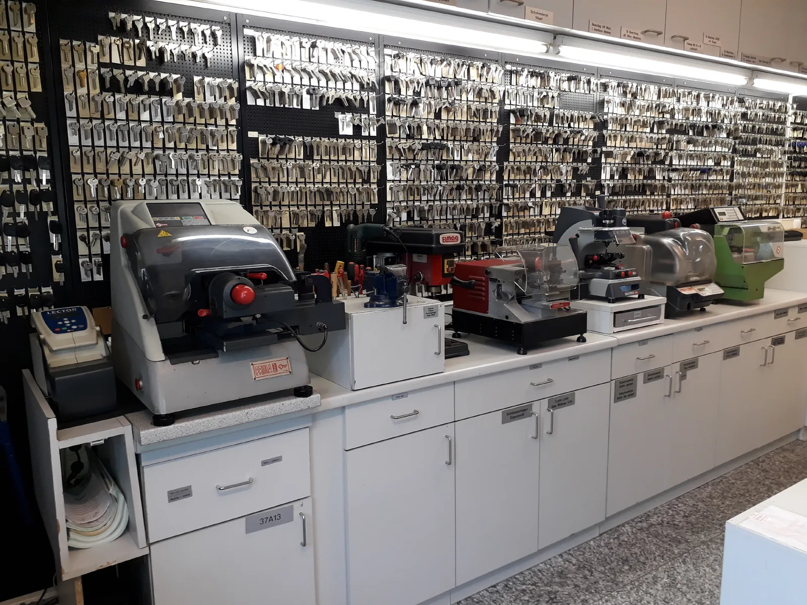 Werkbank mit Schlüsselfräsmaschinen vor einer großen Schlüsselwand